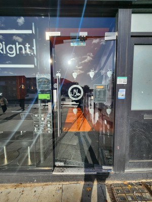 Glass door with silver handle on left. Push to open.