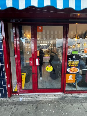 Glass door with red frame. Push handle on left to open. One step up at foot of door.