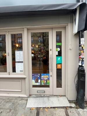 White framed glass door with metal handle to right. Push to open.