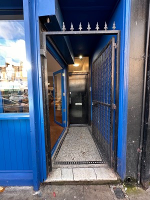 First blue and black metal gated door ahead. Push from left to open.