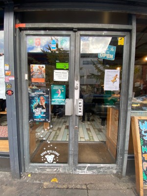 Glass doors with grey frames straight ahead. Push handles in centre to open.