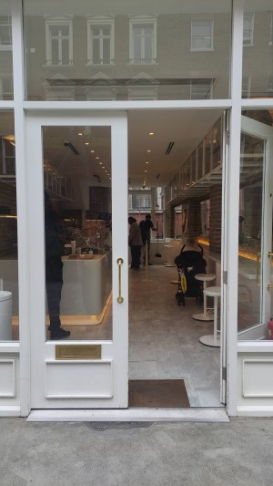 Glass doors with white frames ahead. Push vertical gold handles in centre to open.