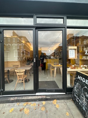 Glass door with black frame ahead. Push to open via black handle on left.