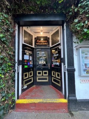 From street facing venue. Black frames glass door with metal handle to right. Pull to open.