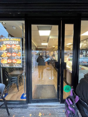 Glass door with black frame ahead. Push to open via black handle on right.