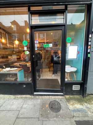 Glass door with black frame. Push to open via black handle on left.
