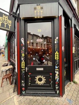 Black framed glass door with metal handle to left. Push to open.