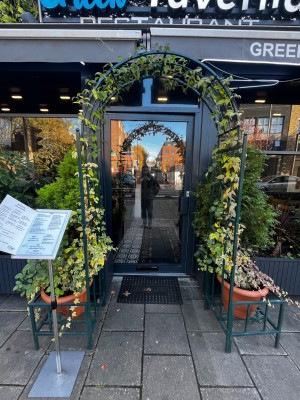 Metal standing archway leading to glass door with black frame. Push from right to open. Very small step at foot of door.