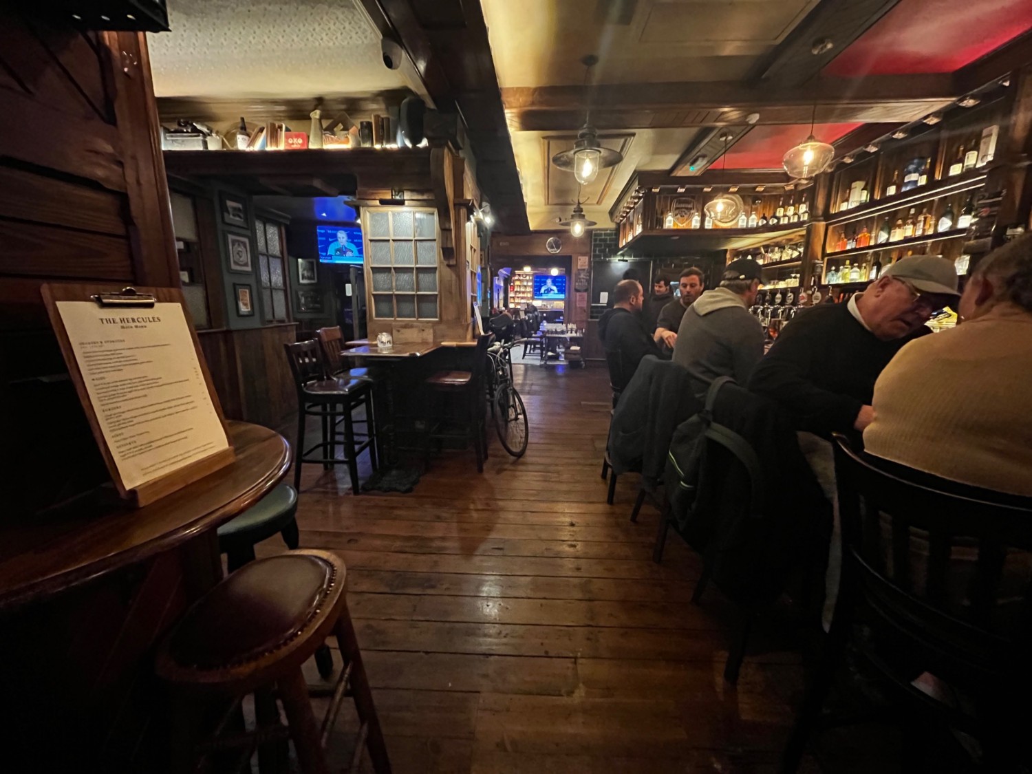Facing left from half booths along right wall. Bar counter with backed stools along right wall. High tables with stools along left.