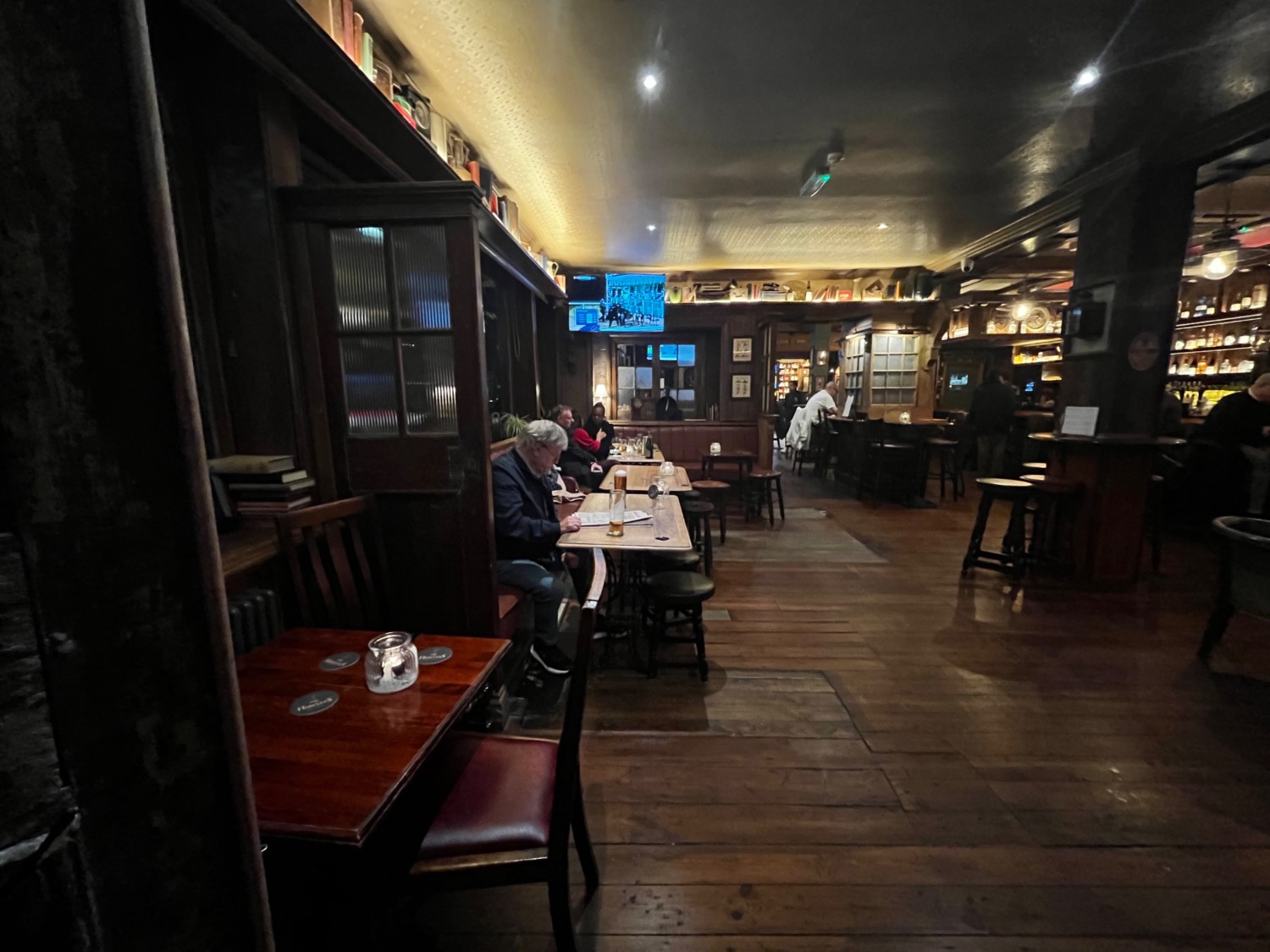 From entrance facing slightly left. Tables with chairs along left wall directly ahead followed by half booth on back wall.