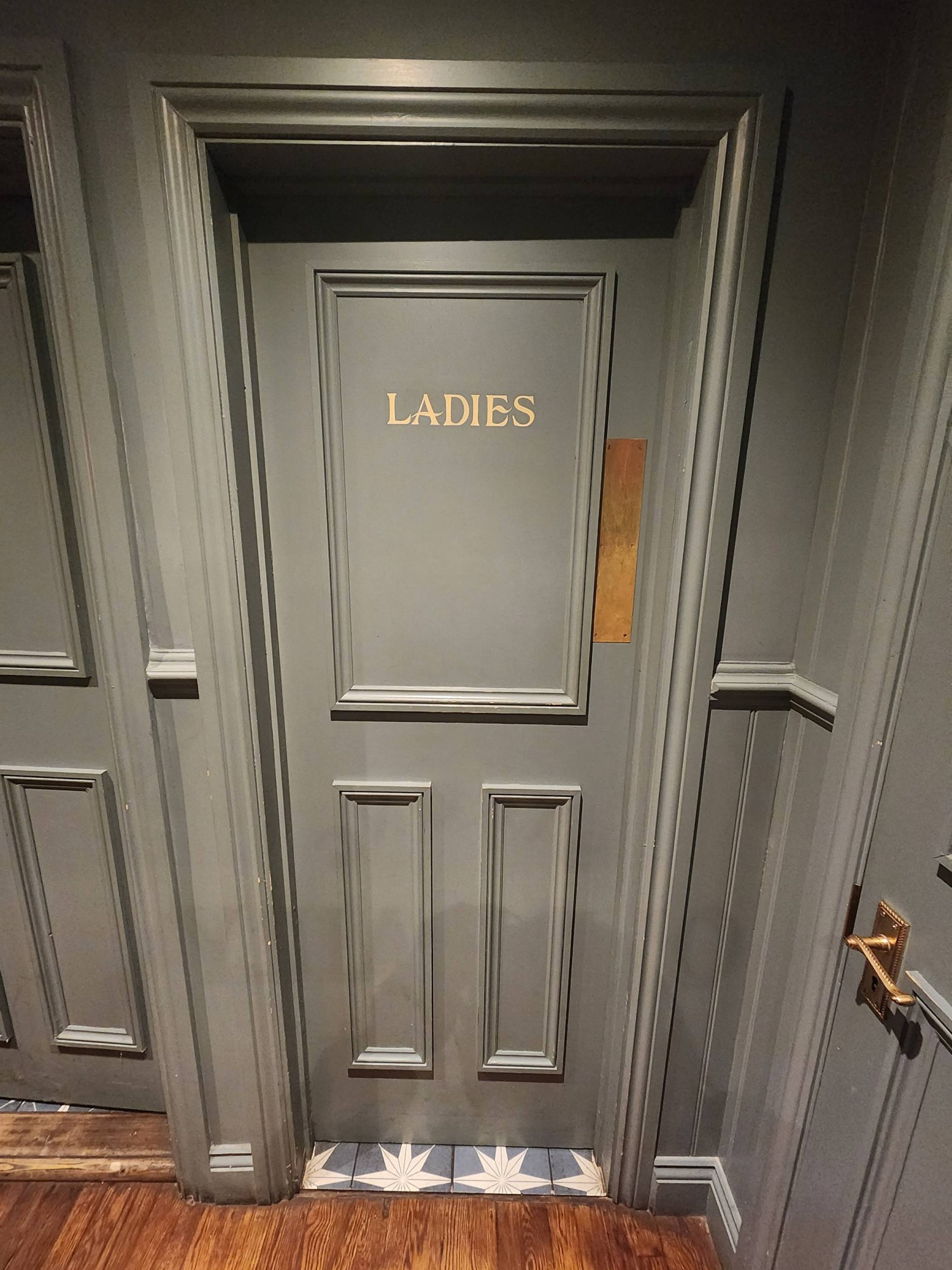 From end of path, looking left. Ladies room door ahead. Push from right to open.