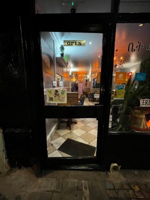 Glass door with black frame. One step up through door. Push from right to open.