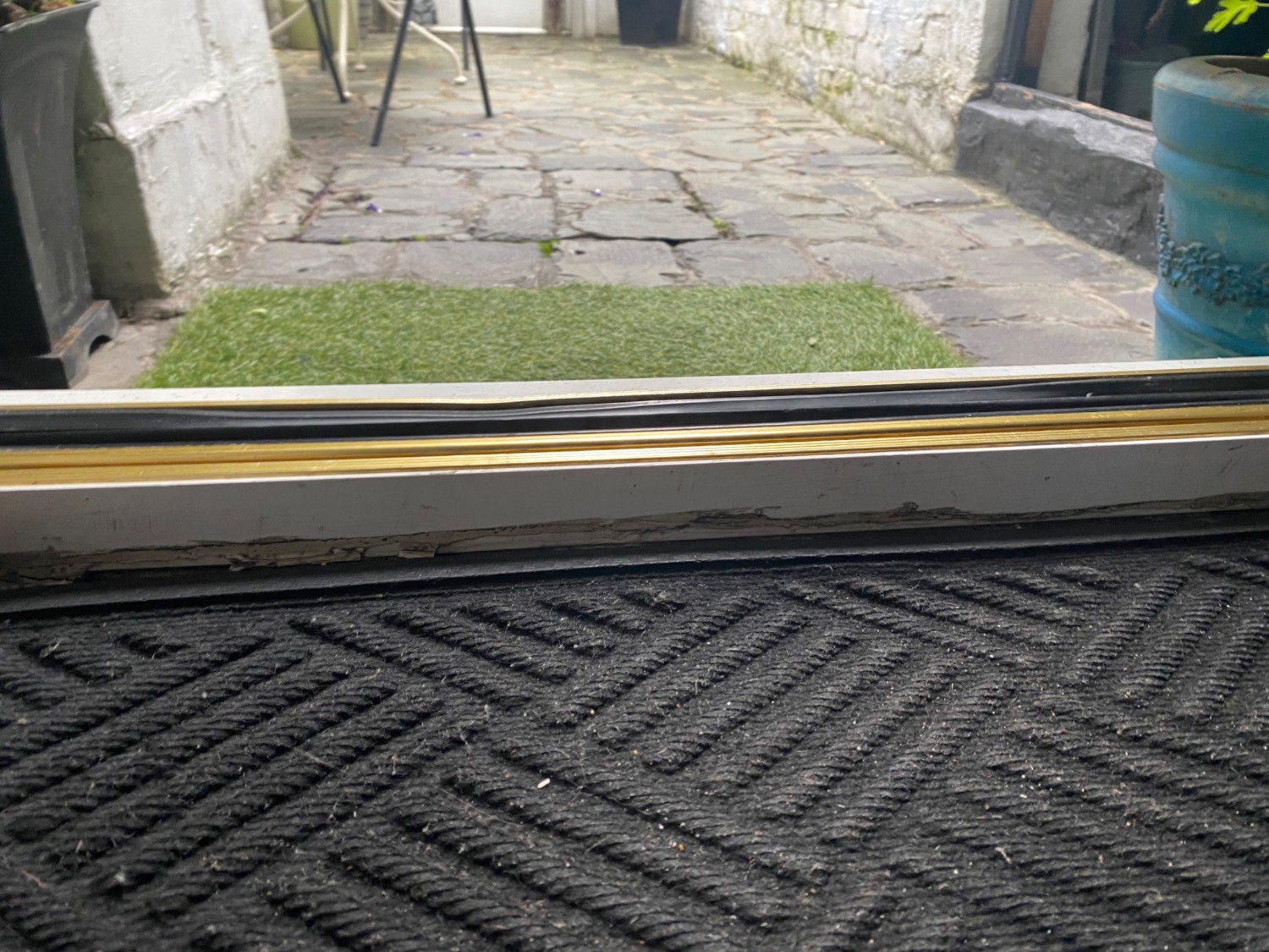 Doormat before door. Raised edge on threshold of door going down to a large step.