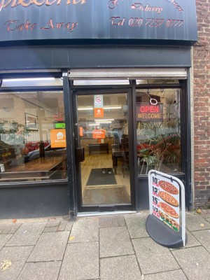 Glass door with black metal frame. Push from left to open.
