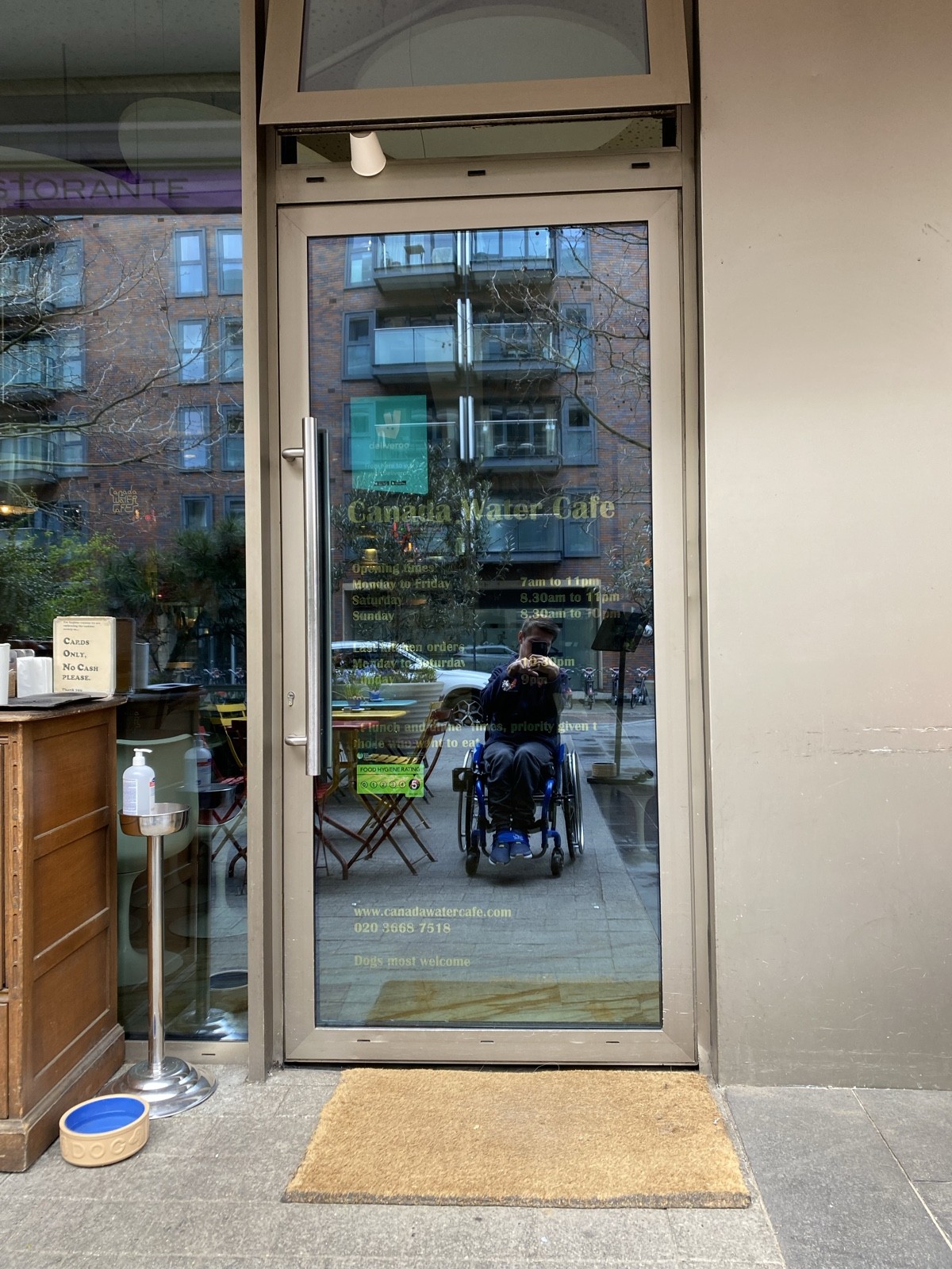 From after opening facing straight. Glass door ahead. Push from metal handle on left to open.