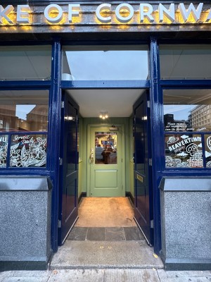 Blue wooden double doors pushed from centre framed by glass windows. Double set of doors with carpeted area inbetween. Green wood and glass door.