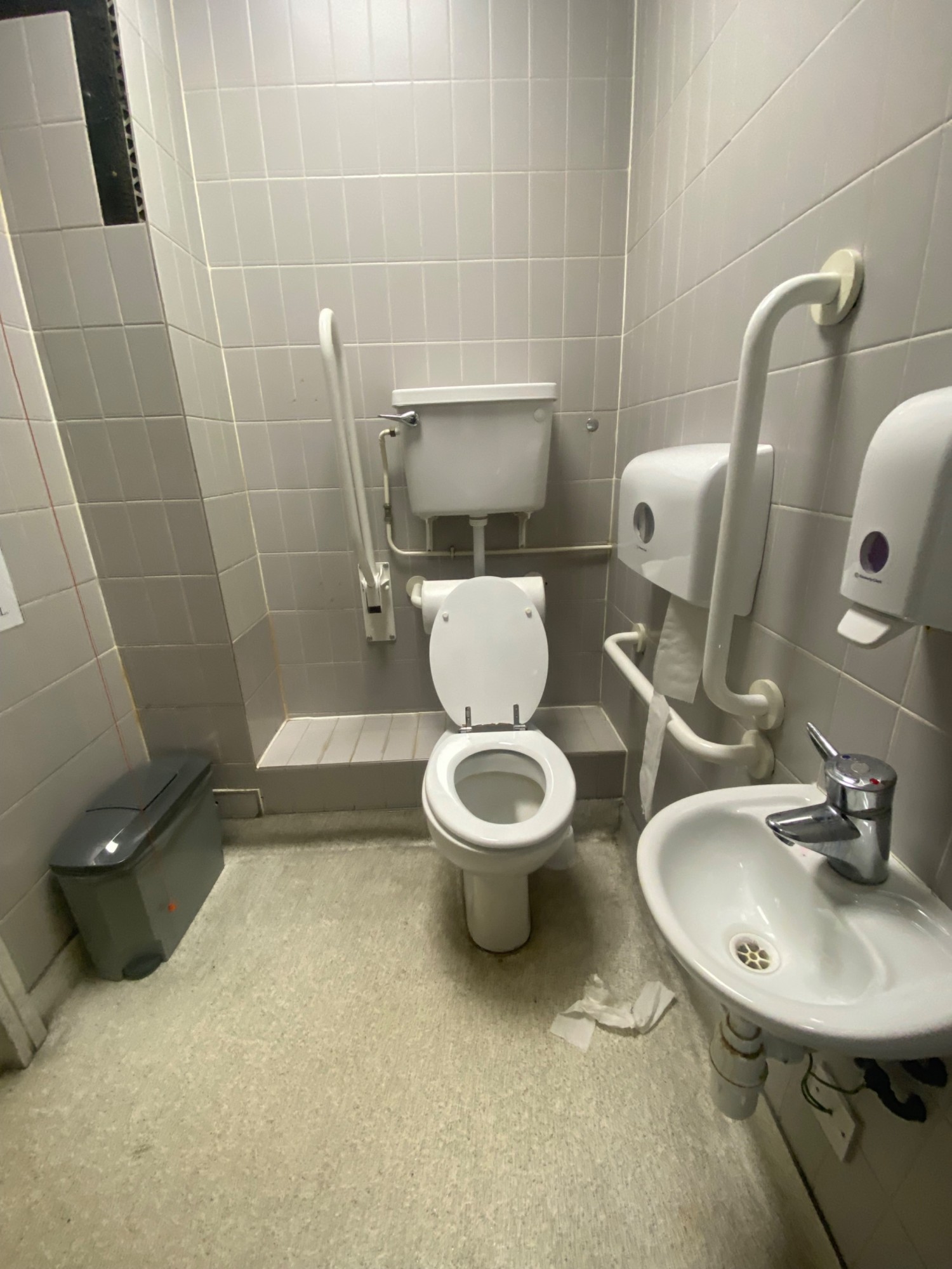 From doorway, facing left. Sink on right. Toilet at back. Emergency pull cord to it's left.