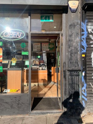 Glass door with black, metal frame. Push black handle on left to open.