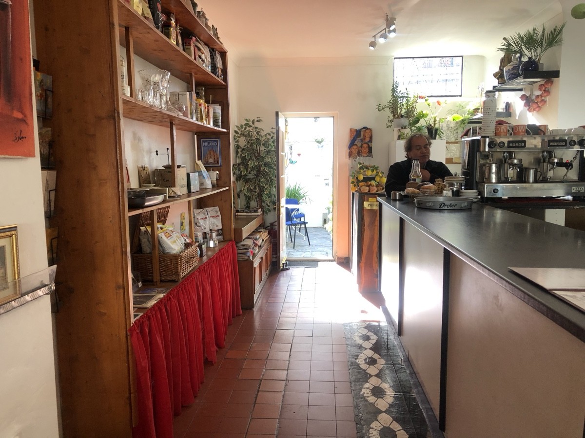 From beginning of counter facing straight. Product shelves on left. Path to outdoor area ahead.