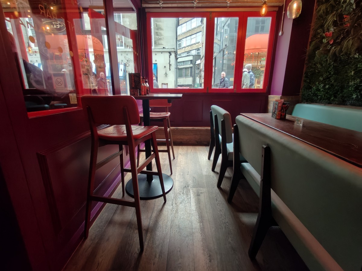 From before half booths facing left. High table and stools on left. Half booth along right.