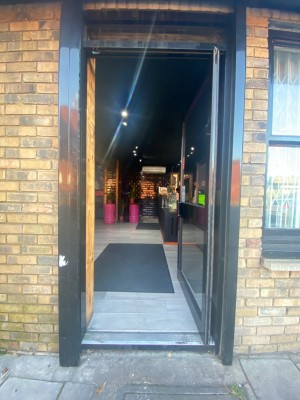 Glass door with black frame. Push from left to open. 1 step in doorway.