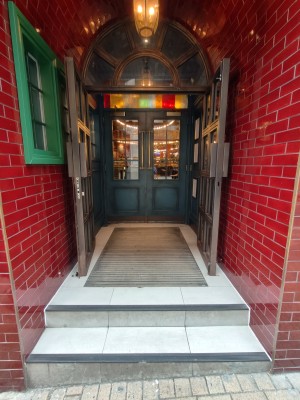 Facing double brown framed glass doors. Pull brown metal handles in centre to open.
