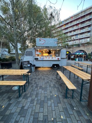 Form street, facing venue. Path ahead to food truck. Seating on both sides.