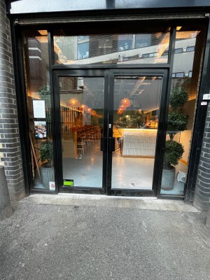 Glass double doors with black frame. Small built in ramp leading to door.