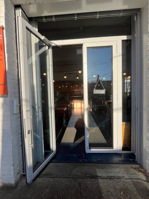 White framed glass door with metal handles in middle. Pull to open.