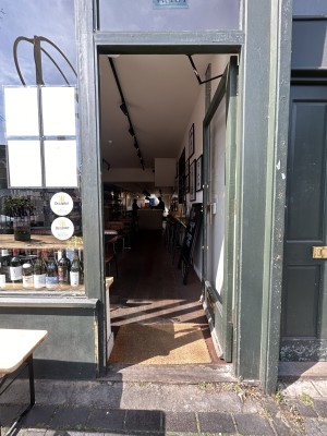 Glass door ahead with green frame. Push from left to open.