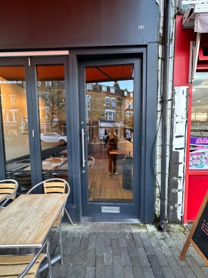 Glass door with blue frame and metal handle. Push from left to open.