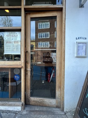 Glass door with wooden frame. Push gold handle on left to open.