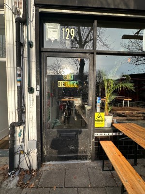 Glass door with black frame. Push handle on right to open.