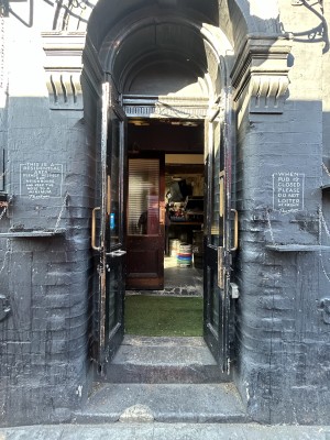 Black wooden doors ahead with glass panels. Pull gold handles in centre to open.