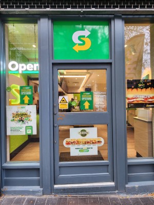 Glass door with grey frame. Push from left to open
