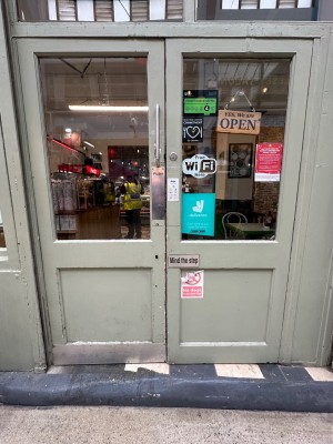 Looking ahead from pavement at double glass and wood doors. Push from centre to left.