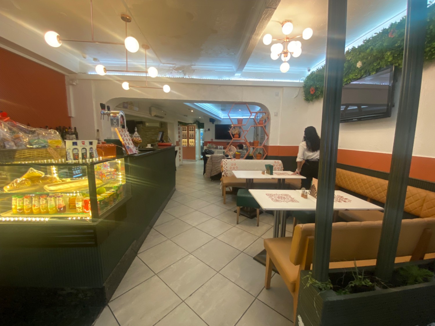 From beginning of counter, looking ahead. Counter along left wall. Half booth and benches along right wall.