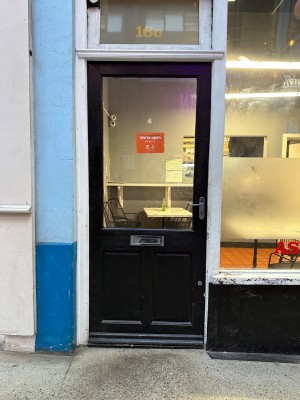 Black wood and glass paneled door with white  doorframe. Handle on right push to open.