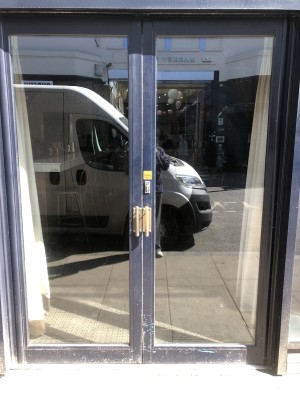 Glass doors with dark blue frame. Push handle in centre to open.