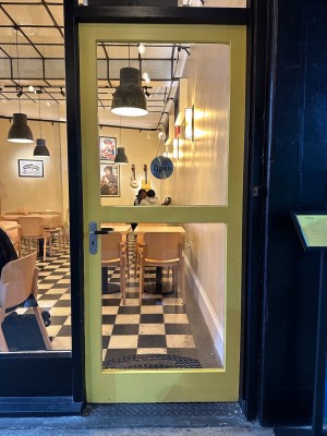 Glass door with yellow frame. Push down metal handle on left to open