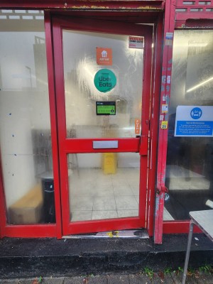 Glass door with red fraMe ahead. Handle on right. Push to open.