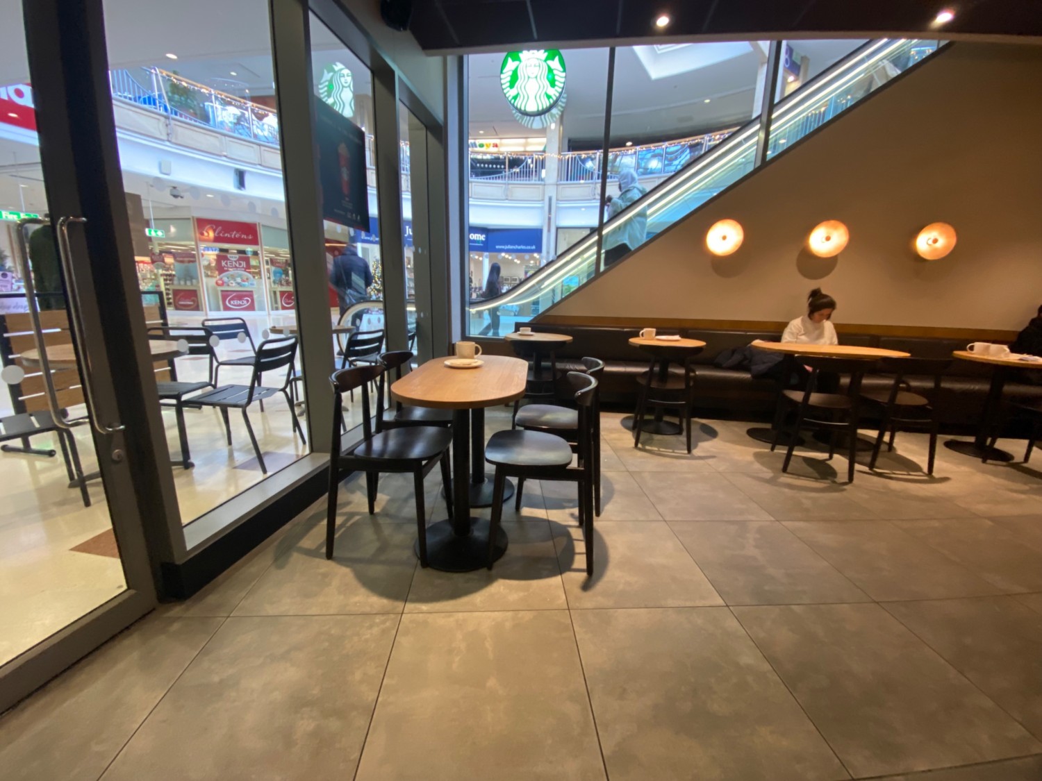 Taking right turn of path. Path leads straight, then right. Side entrance leading to outdoor area, then tables, chairs to left. Half booths at back.