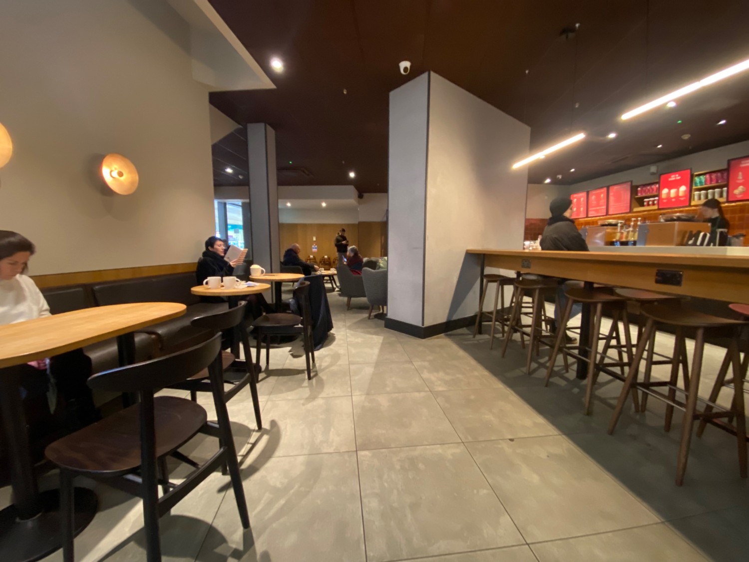 Taking right turn of path facing straight.
Path leads straight to open archway leading to couches. High tables, stools to right. Half booths to left.