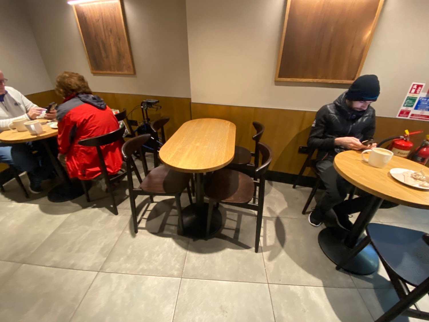 From end of path facing straight. Tables, chairs along back wall. Path leads right to more seating or left to toilet.