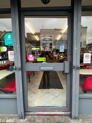 Glass door with grey frame. Push handle on right to open.
