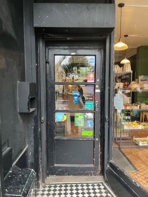 Black framed glass door with metal handle to right. Push to open.