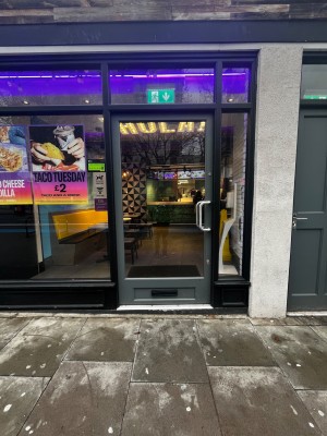 Glass door with grey frame. Push handle on right to open.