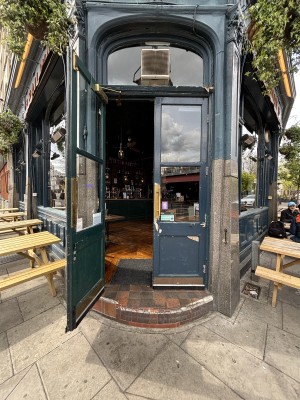 Glass doors with blue frame ahead. Pull doors to open via brass handles in center.