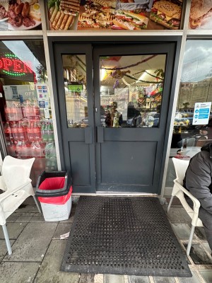 From street, facing cafe front. Double glass doors with handles in middle. Push to open.