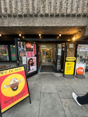 Glass door with black metal frame. Pull black metal handle from right. Signage obstructing on left. Door typically open.